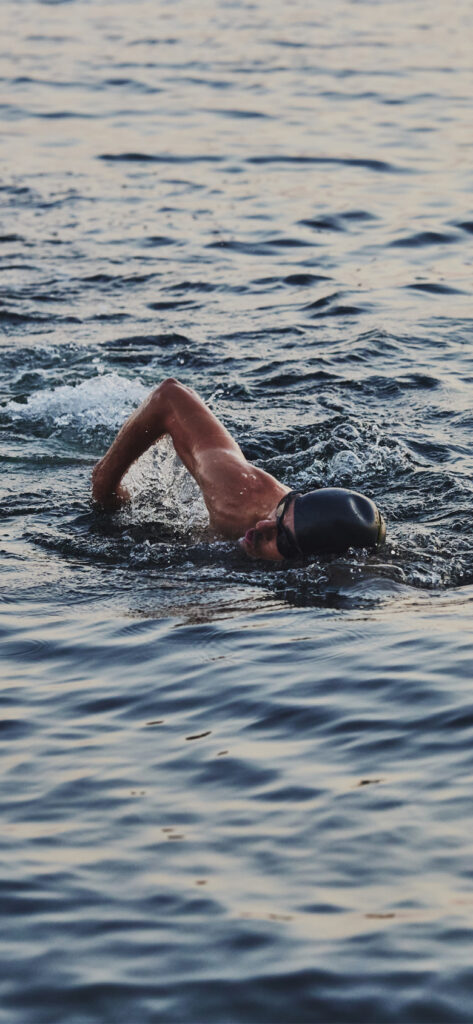 Swimmer in ocean wearing reusable earplugs to prevent swimmer's ear