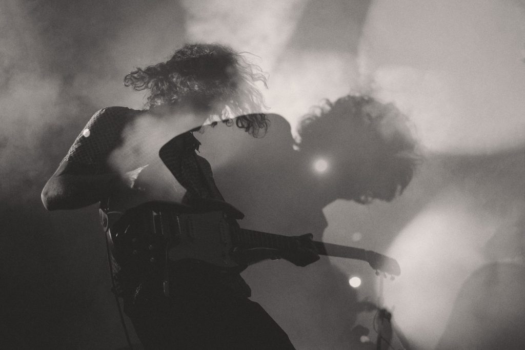 the siluette and shadow of a rock star playing the guitar on a smokey stage